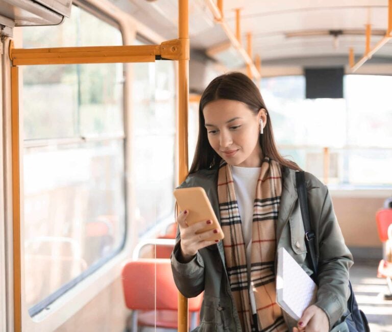 mujer con auriculares practicando chino y japonés en su movil mientras va en transporte público