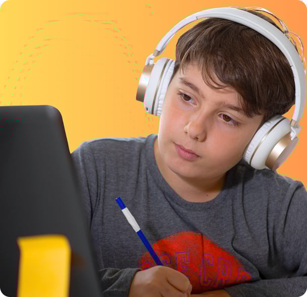 Niño con una camiseta gris escuchando musica con cascos mientras estudia con la tablet